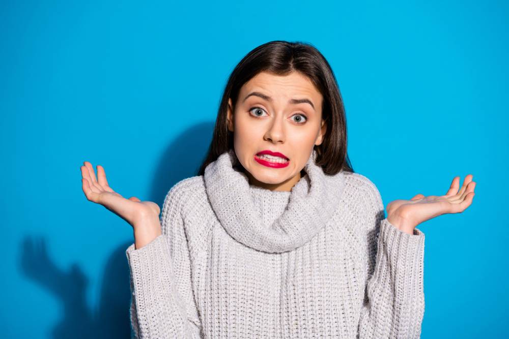 woman in cardigan shrugging against blue background