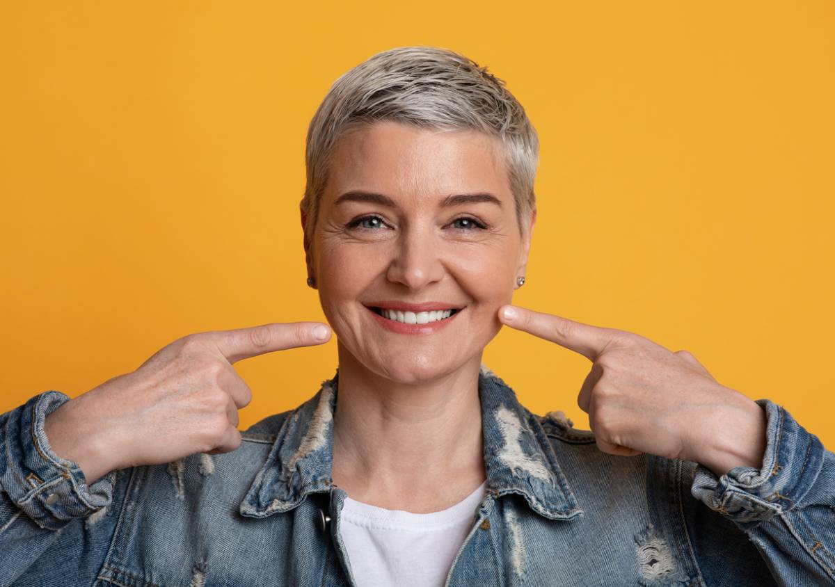 woman pointing at smile against orange background