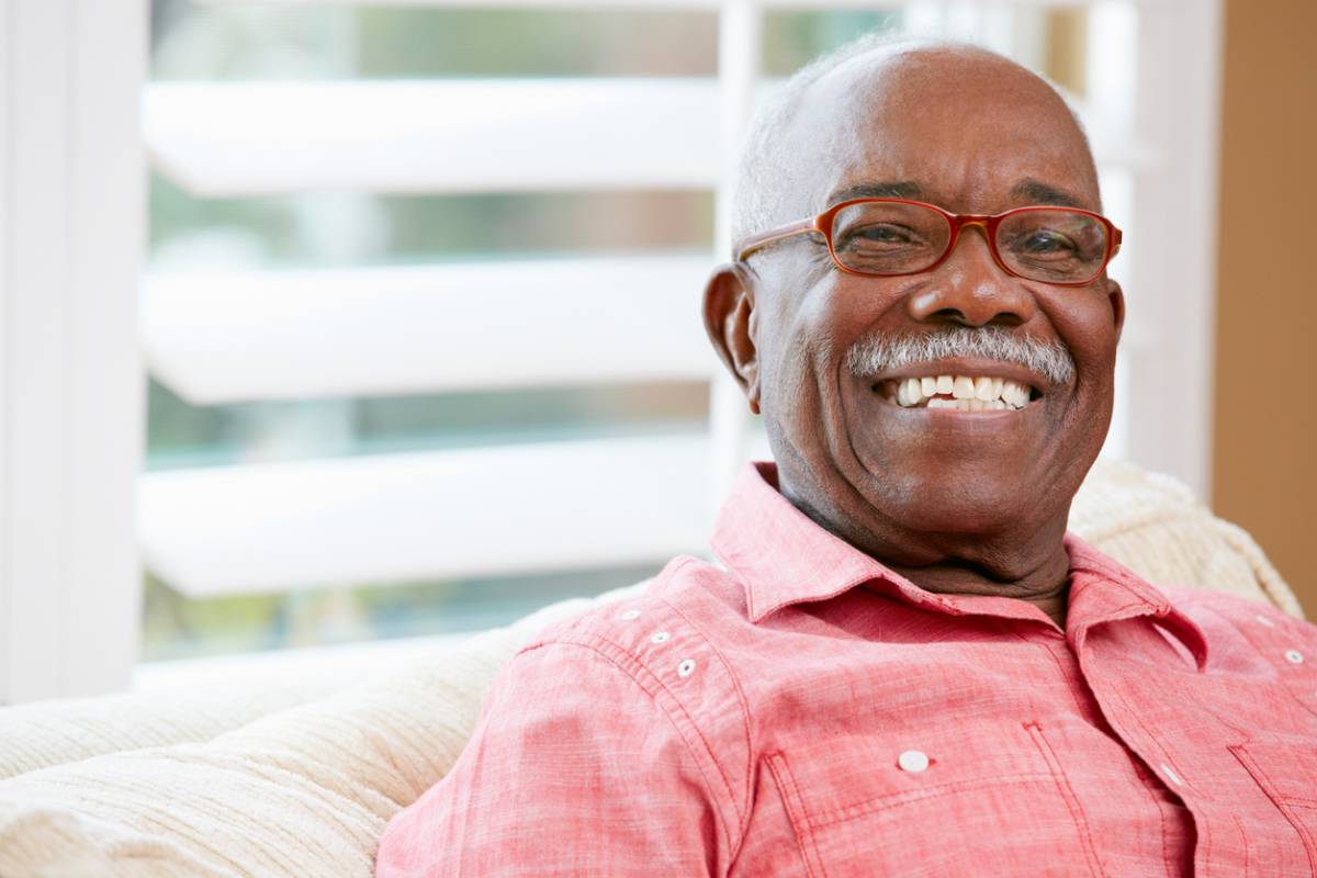 smiling man on couch with glasses (the man has the glasses not the couch)