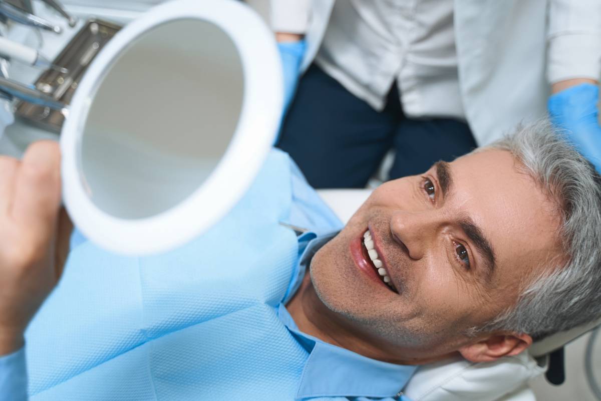 Man sitting in chair looking at new dental implants.