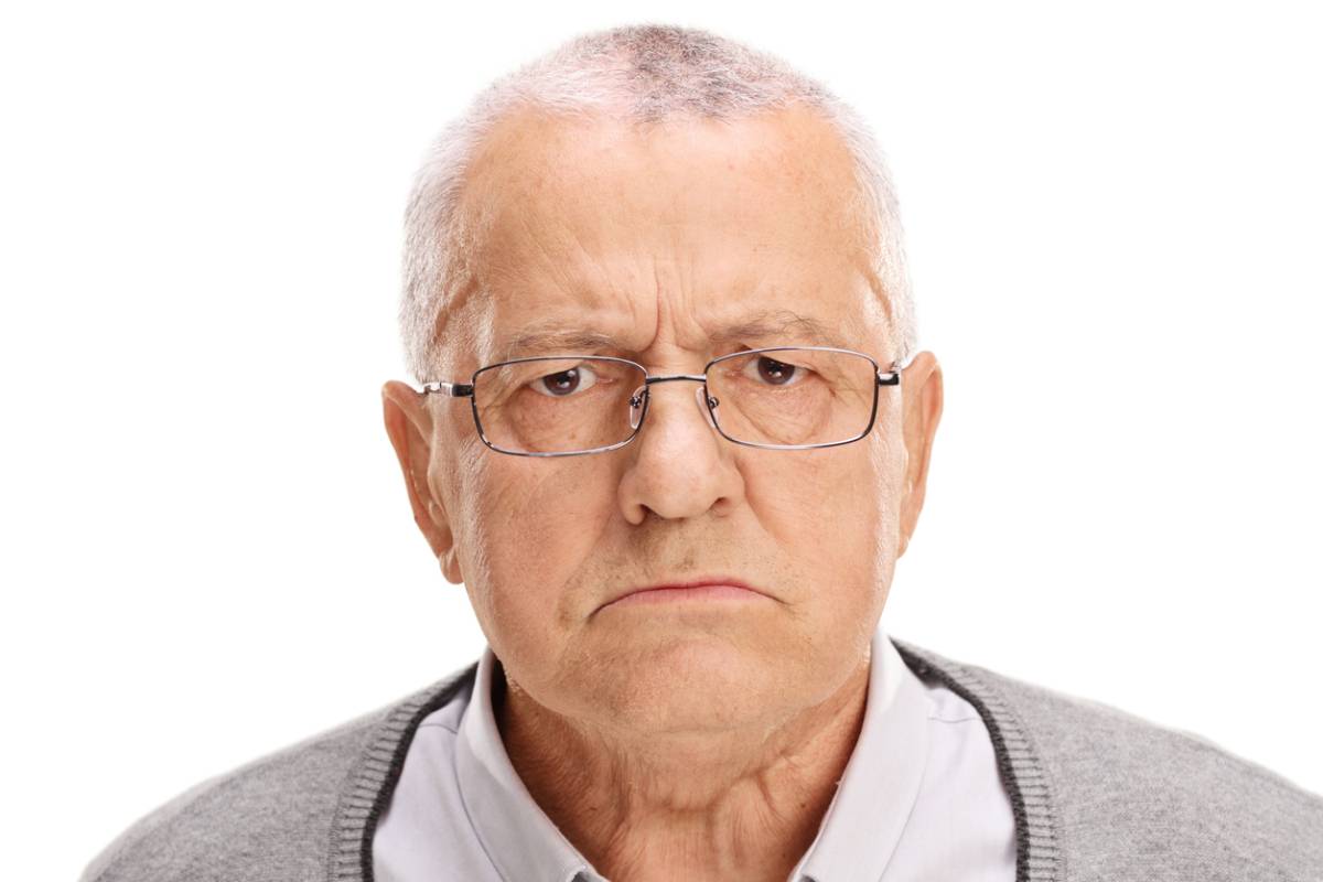 Older man looking unhappy about how missing teeth affect his face. 